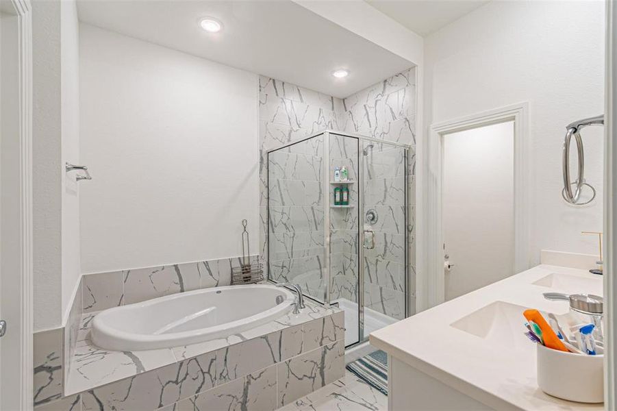 Full bath with a marble finish shower, a bath, double vanity, and recessed lighting