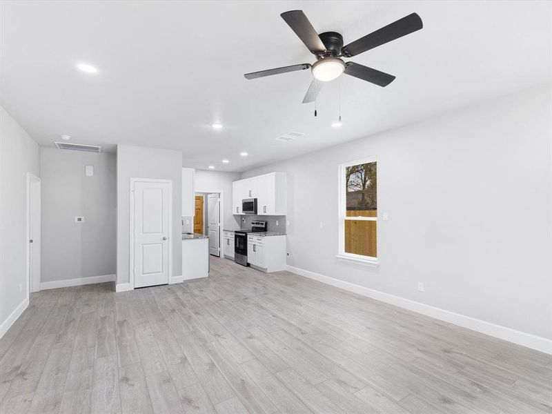 Unfurnished living room with a ceiling fan, recessed lighting, and light wood-type flooring