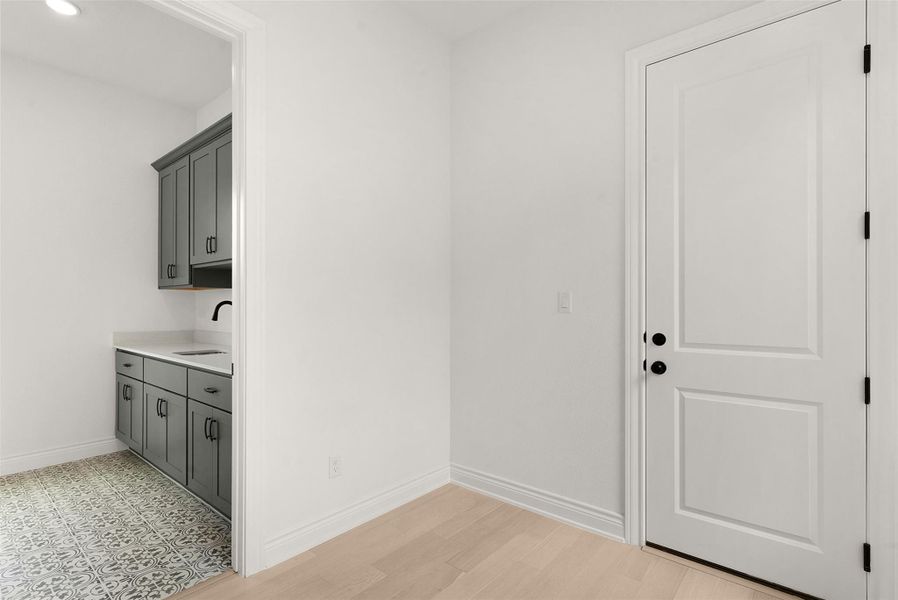 A well-appointed utility room features a functional sink, ample cabinetry, and patterned flooring.
