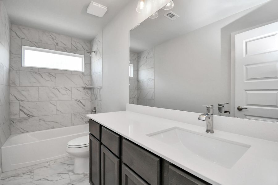 Secondary bath features tile flooring, bath/shower combo with tile surround, light stained wood cabinets, beautiful light countertop. Secondary bath features tile flooring, bath/shower combo with tile surround, light stained wood cabinets, beautiful light countertop.