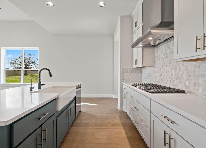 Kitchen featuring recessed lighting, a sink, stainless steel appliances, wall chimney exhaust hood, and baseboards Kitchen featuring recessed lighting, a sink, stainless steel appliances, wall chimney exhaust hood, and baseboards