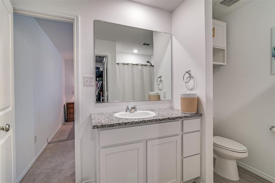 Bathroom with toilet, vanity, and curtained shower