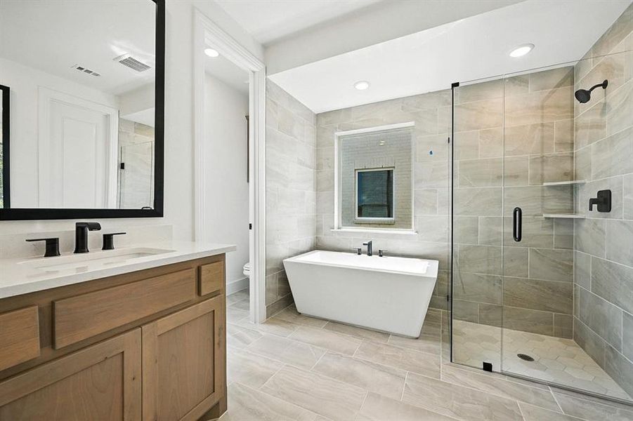 Full bathroom featuring vanity, a stall shower, tile walls, a freestanding bath, and recessed lighting Full bathroom featuring vanity, a stall shower, tile walls, a freestanding bath, and recessed lighting