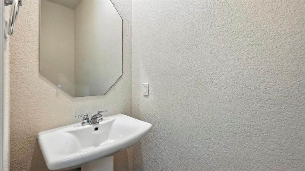 Pedestal sink with chrome faucet and octagonal wall mirror