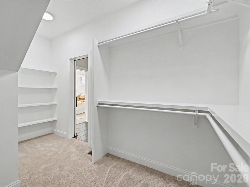 Large walk-in primary closet with built-in shelving and abundant hanging space provides exceptional storage and organization.