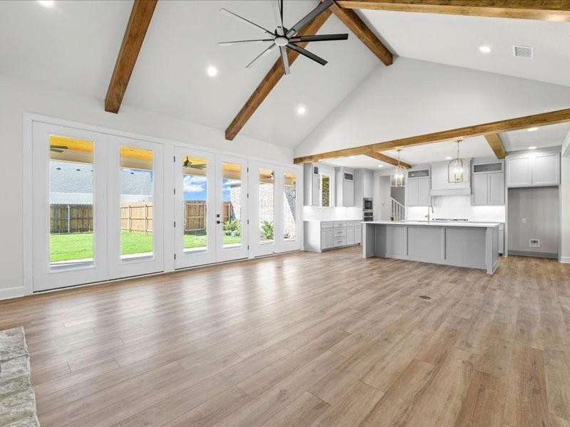 Unfurnished living room with recessed lighting, high vaulted ceiling, beam ceiling, ceiling fan, and light wood-style flooring Unfurnished living room with recessed lighting, high vaulted ceiling, beam ceiling, ceiling fan, and light wood-style flooring