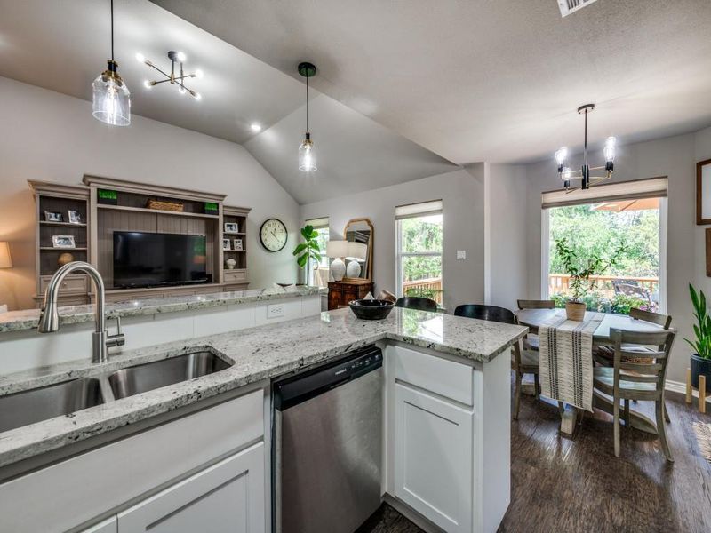 Kitchen featuring dishwasher, a sink, open floor plan, vaulted ceiling, and dark wood-type flooring Kitchen featuring dishwasher, a sink, open floor plan, vaulted ceiling, and dark wood-type flooring