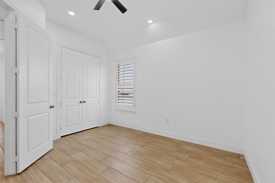 Bright room featuring wood-finish flooring, white walls, and a ceiling fan Bright room featuring wood-finish flooring, white walls, and a ceiling fan
