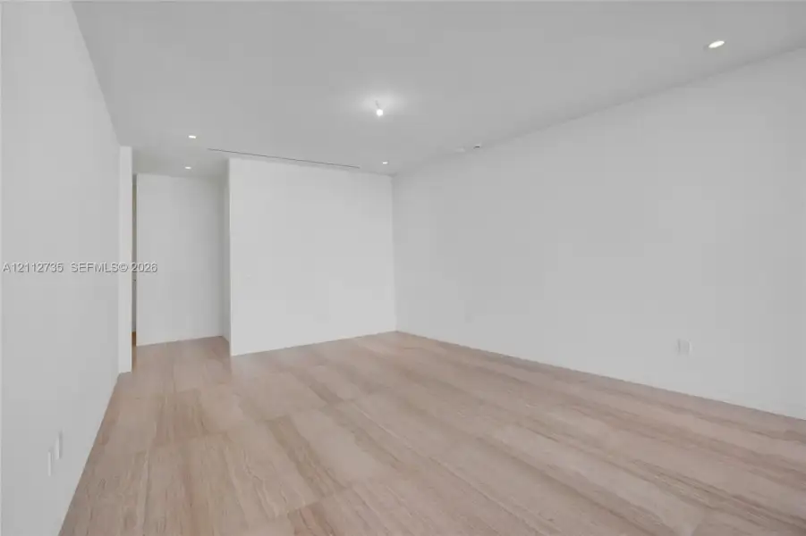 Neutral-toned interior space featuring wood-finish flooring, crisp white walls, and recessed ceiling lighting