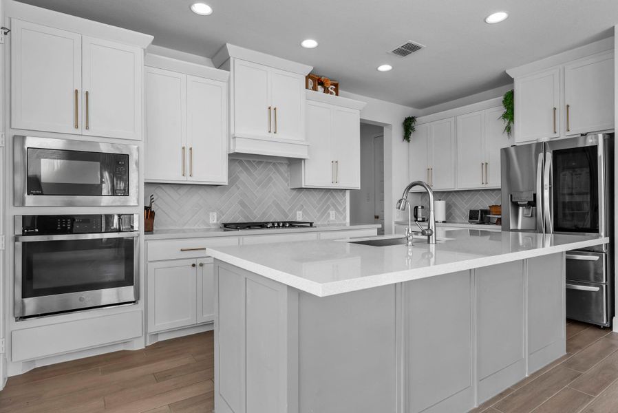 Kitchen featuring stainless steel appliances, white cabinetry, light wood-type flooring, a kitchen island with sink, and recessed lighting