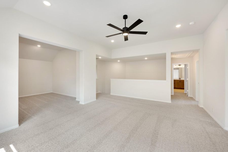 Spacious master bedroom with carpet, black ceiling fan, walk-in closet, and ensuite bathroom doorway visible. Spacious master bedroom with carpet, black ceiling fan, walk-in closet, and ensuite bathroom doorway visible.
