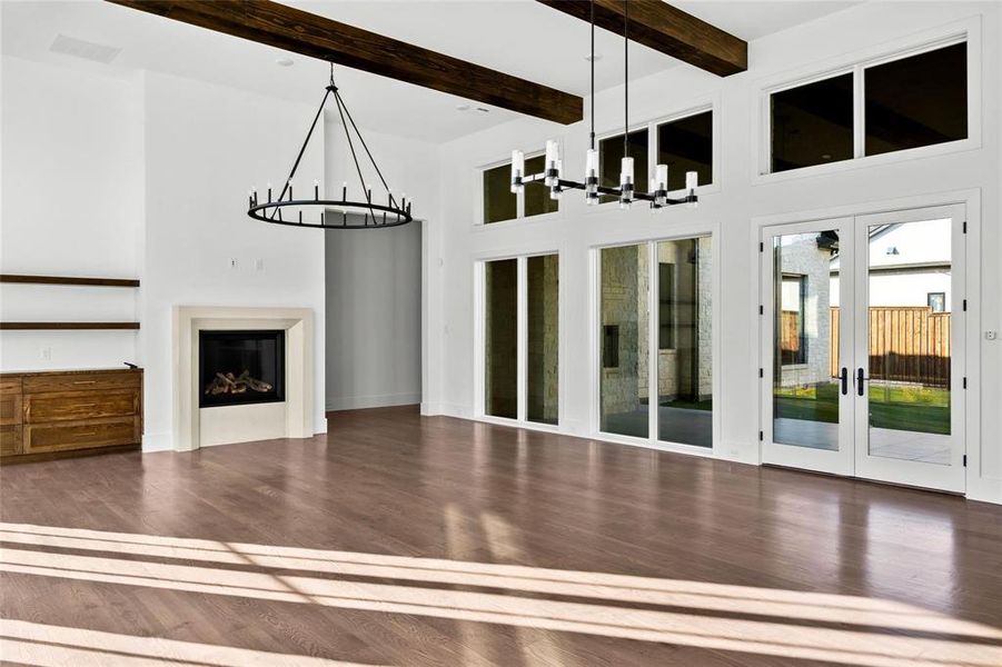 Unfurnished living room featuring a chandelier, a fireplace, beamed ceiling, dark wood-style floors, and a high ceiling Unfurnished living room featuring a chandelier, a fireplace, beamed ceiling, dark wood-style floors, and a high ceiling