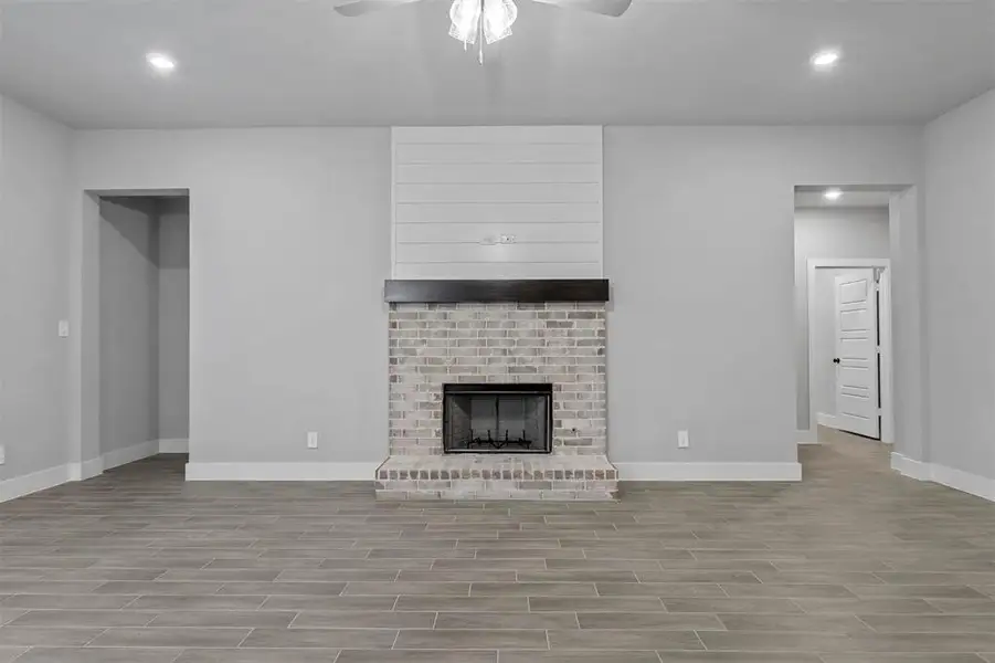 Unfurnished living room featuring ceiling fan, light hardwood / wood-style floors, and a fireplace