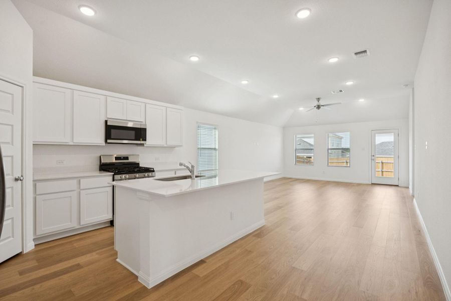 Kitchen with a ceiling fan, light wood-style flooring, stainless steel appliances, white cabinetry, and light countertops
