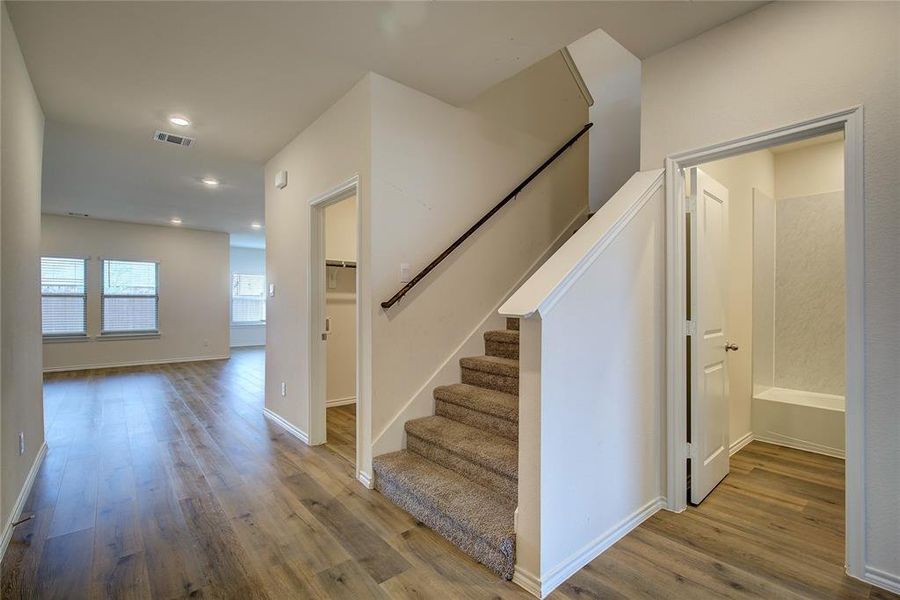 Staircase with wood finished floors and recessed lighting