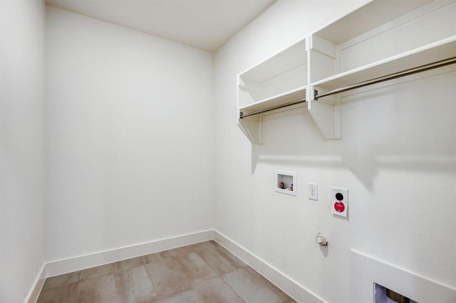 Utility room featuring built-in shelving, hanging rod, neutral wall paint, tile flooring, and baseboard trim