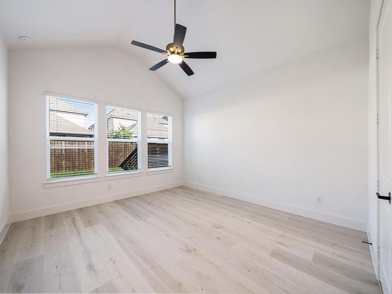 Empty room featuring vaulted ceiling, light wood-type flooring, and ceiling fan