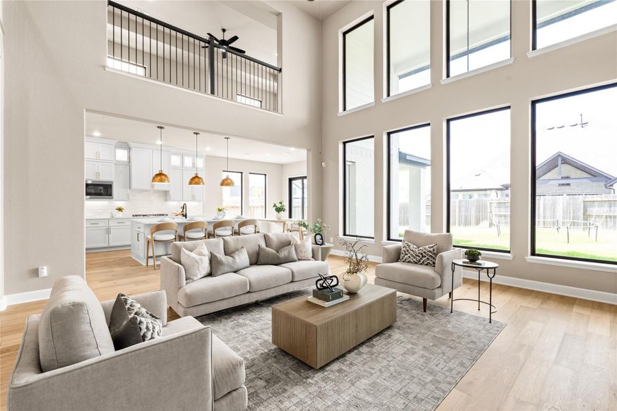 Stunning open-concept living area with soaring ceilings, abundant natural light from floor-to-ceiling windows, and a modern kitchen featuring an island and elegant pendant lighting. *Virtually Staged*