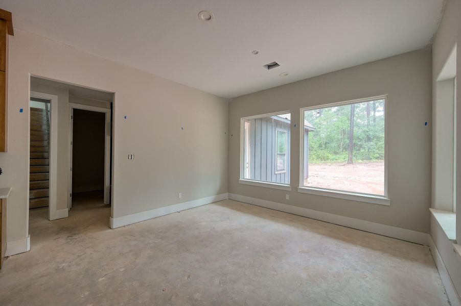 A bright dining room with large windows offers a view of the backyard with greenery.