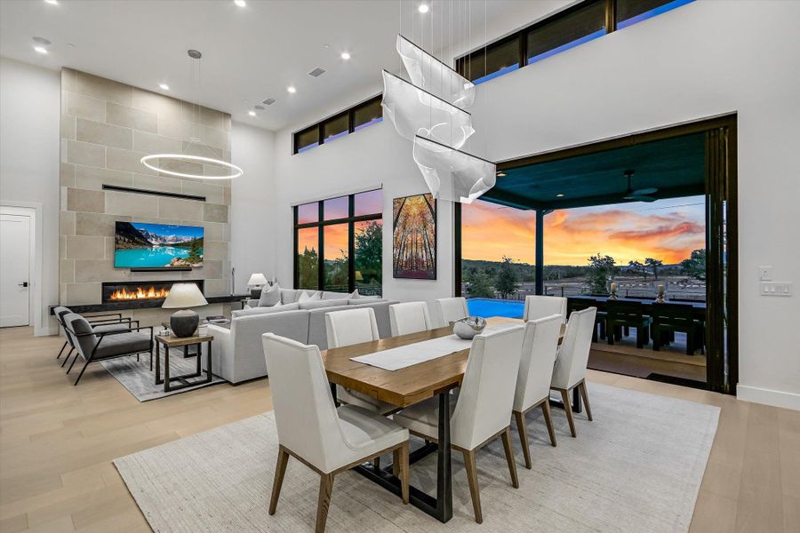 Dining space featuring a high ceiling, light wood-type flooring, a large fireplace, and recessed lighting Dining space featuring a high ceiling, light wood-type flooring, a large fireplace, and recessed lighting