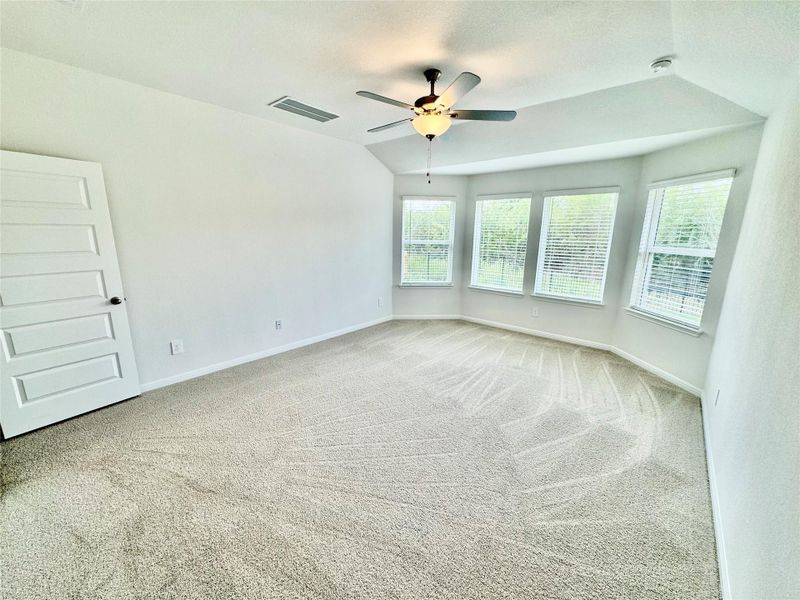Empty room featuring carpet flooring, ceiling fan, lofted ceiling, and a textured ceiling Empty room featuring carpet flooring, ceiling fan, lofted ceiling, and a textured ceiling