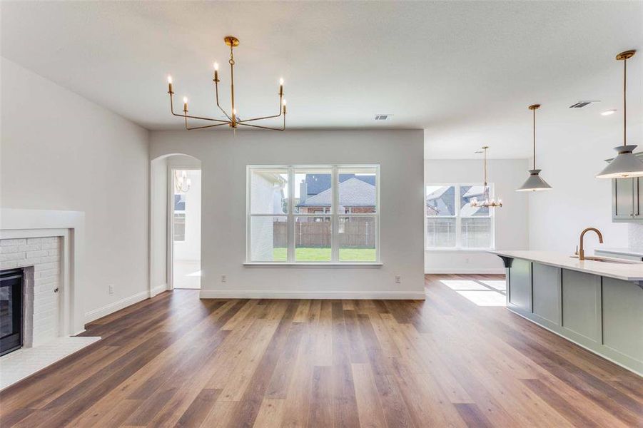 Unfurnished living room featuring a chandelier, a fireplace, hardwood / wood-style floors, and sink