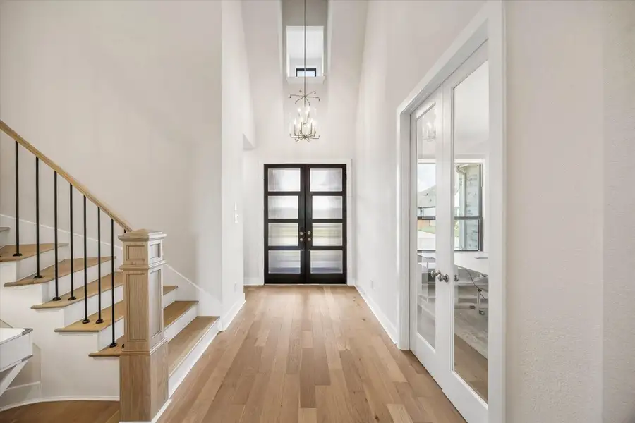 TWO-STORY FOYER WITH A STATEMENT CHANDELIER, MODERN DOUBLE FRONT DOORS, WOOD FLOORING, AND DIRECT ACCESS TO THE PRIVATE STUDY. TWO-STORY FOYER WITH A STATEMENT CHANDELIER, MODERN DOUBLE FRONT DOORS, WOOD FLOORING, AND DIRECT ACCESS TO THE PRIVATE STUDY.