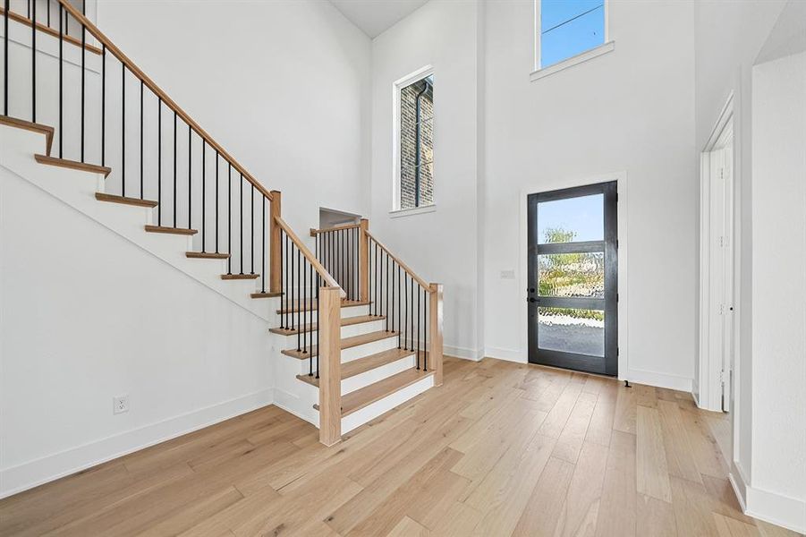 Entrance foyer featuring plenty of natural light, stairway, light wood-type flooring, and a towering ceiling