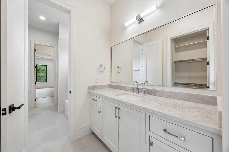 Shared bath features a quartz topped dual vanity, oversized mirror, and a spacious walk in linen closet for added convenience. Bright finishes and a thoughtfully designed layout make mornings easy for adjoining bedrooms.