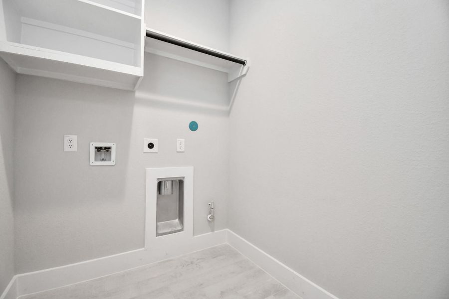 A perfect blend of functionality and comfort. Capture the essence of easy living with a first-floor laundry room, thoughtfully equipped with shelving for effortless organization. Both electric and gas connections available. Sample photo of completed home with similar floor plan. Actual colors and selections may vary.