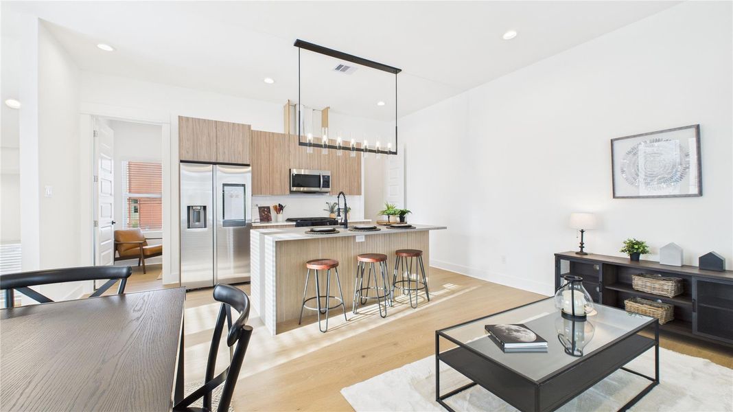 The welcoming second-floor open-concept living area seamlessly combines the living room, dining room, and kitchen, filled with natural light and enhanced by modern finishes and engineered hardwood flooring throughout, creating a bright and inviting space ideal for everyday living and entertaining.