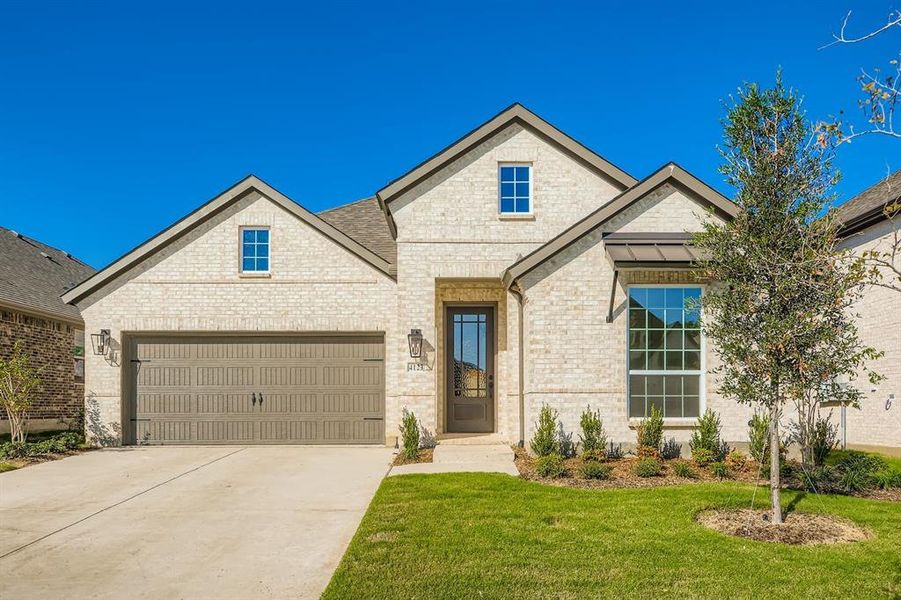 View of front of house with brick siding, driveway, and a front lawn