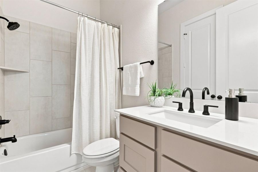 Modern bathroom featuring a vanity with sleek fixtures and a combination shower-tub.