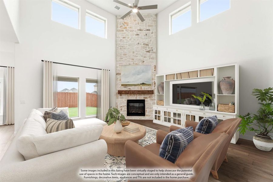 Living room with two-story stone fireplace, high ceilings, ceiling fan, and built-in entertainment center
