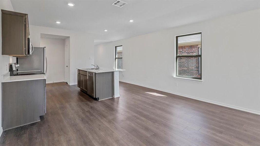 Kitchen with an island with sink, healthy amount of natural light, dark wood-style floors, and recessed lighting Kitchen with an island with sink, healthy amount of natural light, dark wood-style floors, and recessed lighting