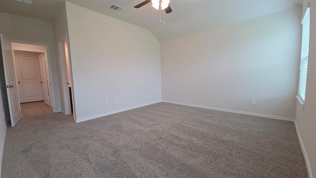Spacious room featuring vaulted ceilings, neutral-toned carpet, and a ceiling fan Spacious room featuring vaulted ceilings, neutral-toned carpet, and a ceiling fan