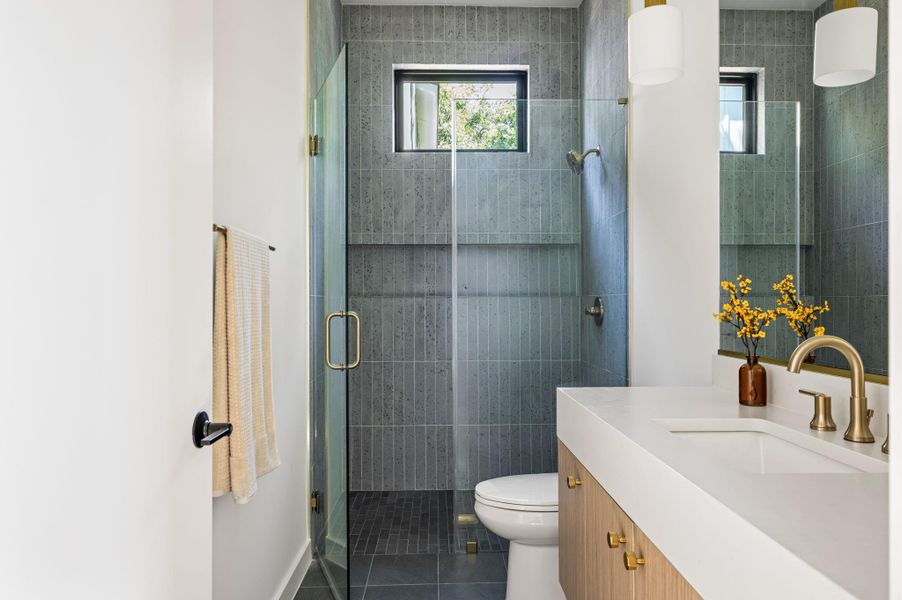 Modern vertical tiling runs from floor to ceiling in a glass-enclosed walk-in shower.