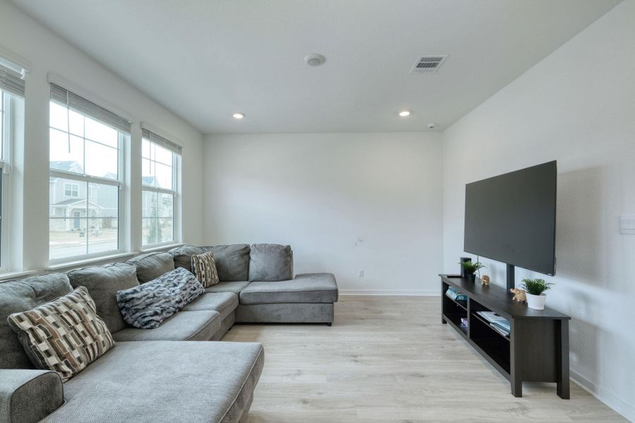 Living room featuring light wood-style floors, baseboards, visible vents, and recessed lighting