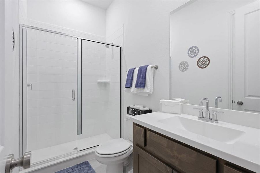 Bathroom featuring a walk-in shower with sliding glass doors, white subway tile surround, single-basin vanity with a white countertop, chrome faucet, and wood-finish cabinetry