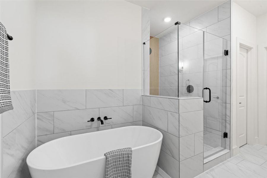 Sleek freestanding bathtub and a spacious glass-enclosed shower. The white and gray tile work enhances the clean, contemporary aesthetic.