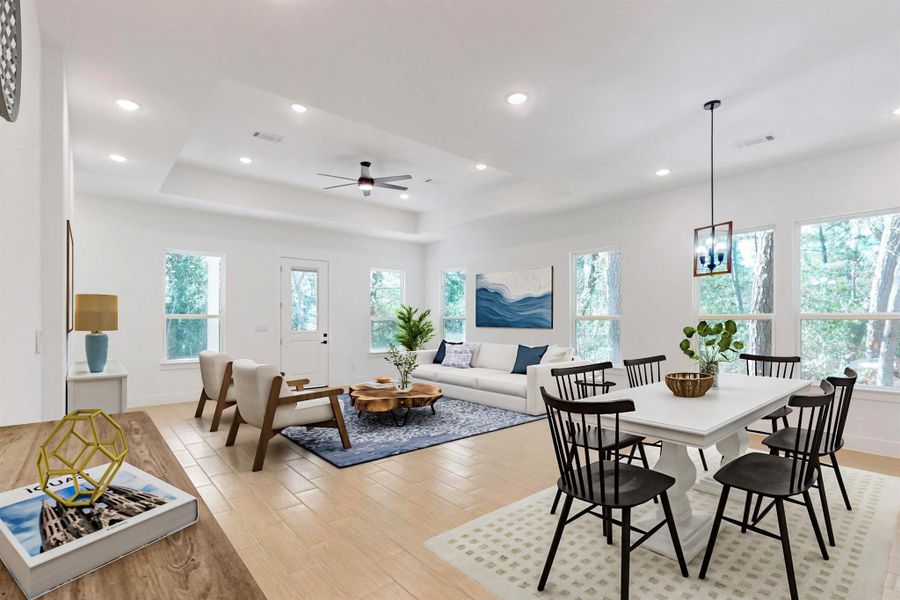 Dining space with a tray ceiling, light wood-type flooring, ceiling fan, and recessed lighting