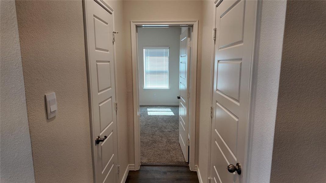 Hall featuring a textured wall and dark wood-style flooring