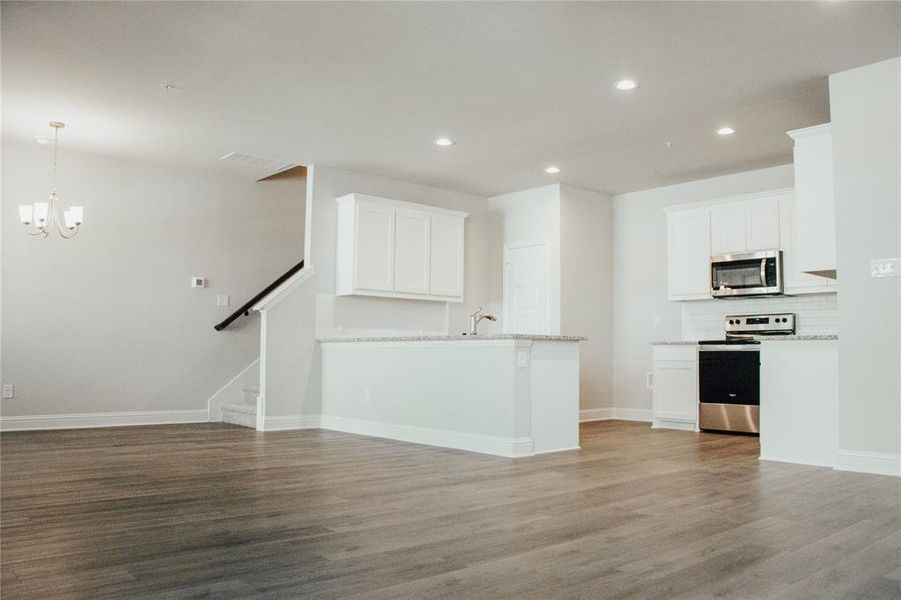 Unfurnished living room with hardwood / wood-style floors, a notable chandelier, and sink