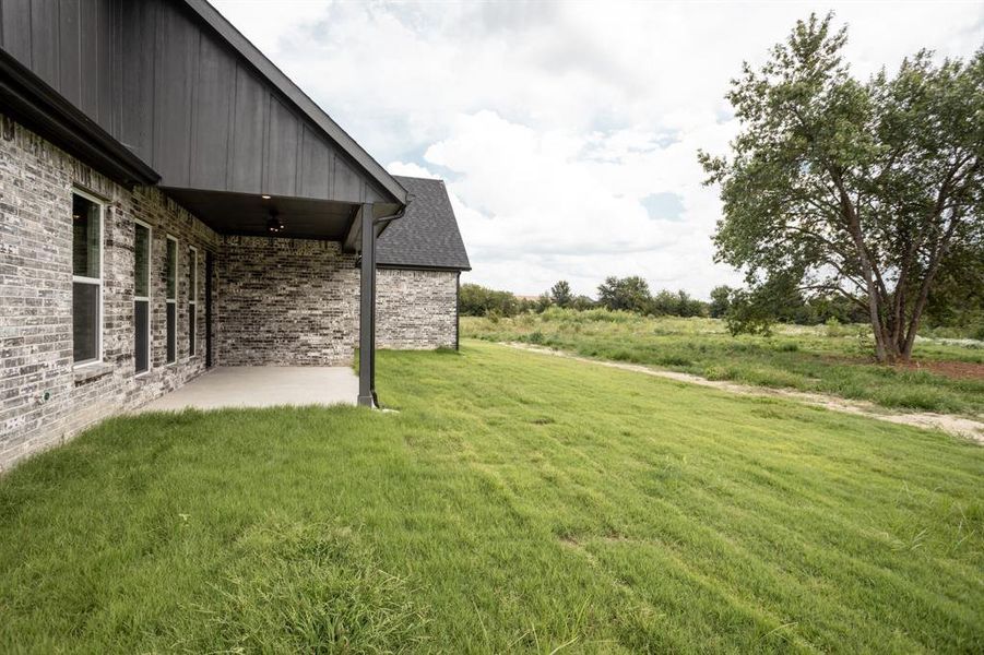 View of grassy yard with a patio and a ceiling fan View of grassy yard with a patio and a ceiling fan