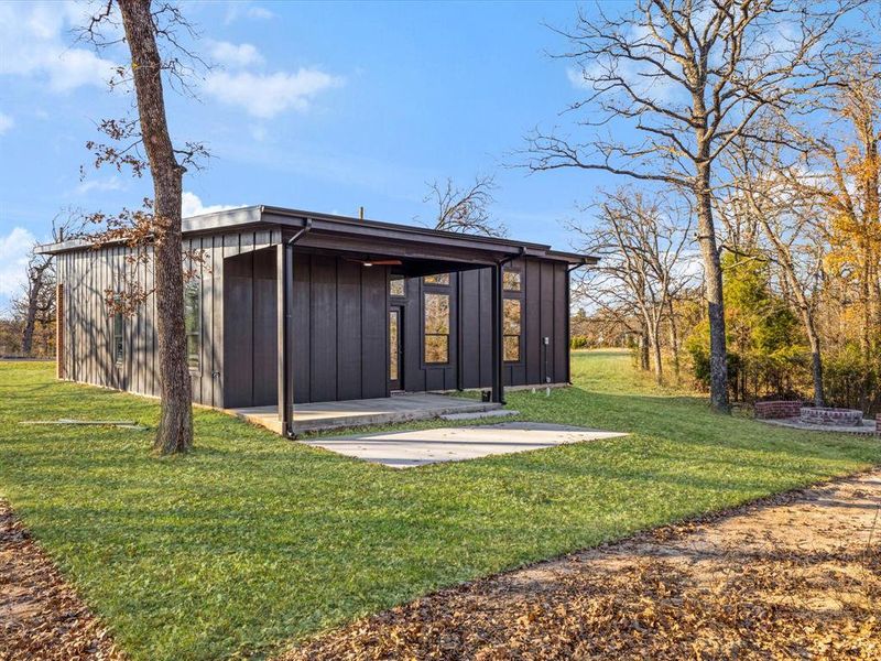 Rear view of house featuring board and batten siding, a patio area, and a lawn