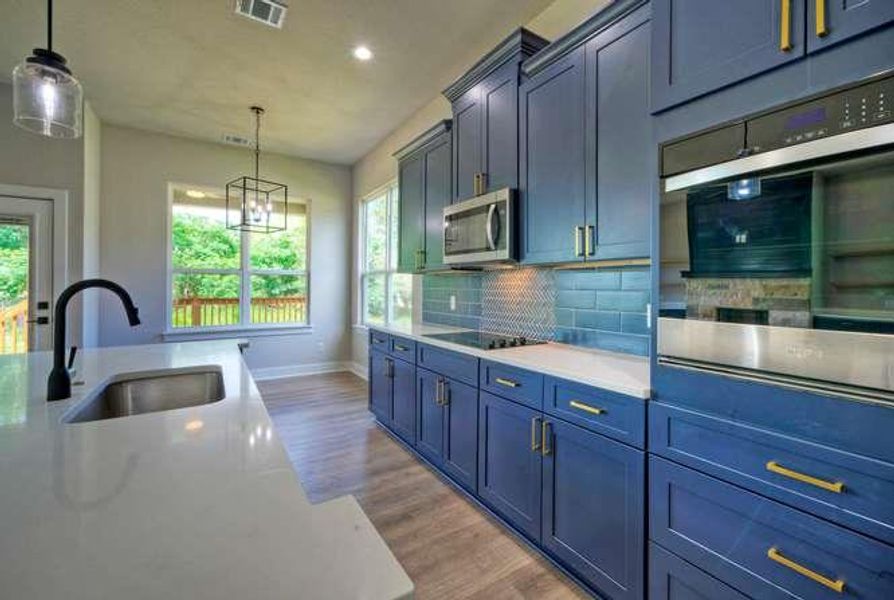 A contemporary kitchen boasts rich blue cabinetry and stainless-steel appliances, ideal for culinary creations.