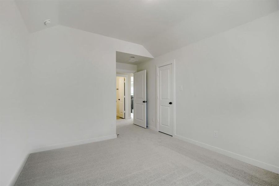 Carpeted room featuring light gray walls, white trim, and white paneled doors with black hardware