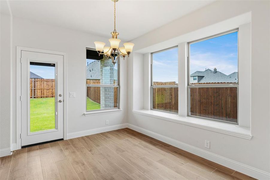 Unfurnished dining area with healthy amount of natural light, a chandelier, and light wood finished floors