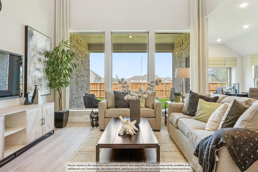Living room with high ceilings, large windows, neutral sofas, and hardwood floors overlooking a backyard