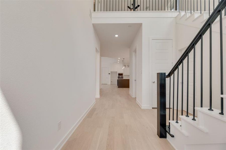 Hall featuring stairs, light wood finished floors, and recessed lighting Hall featuring stairs, light wood finished floors, and recessed lighting